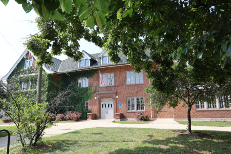 Brick building with ivy-covered walls and a green tiled roof.